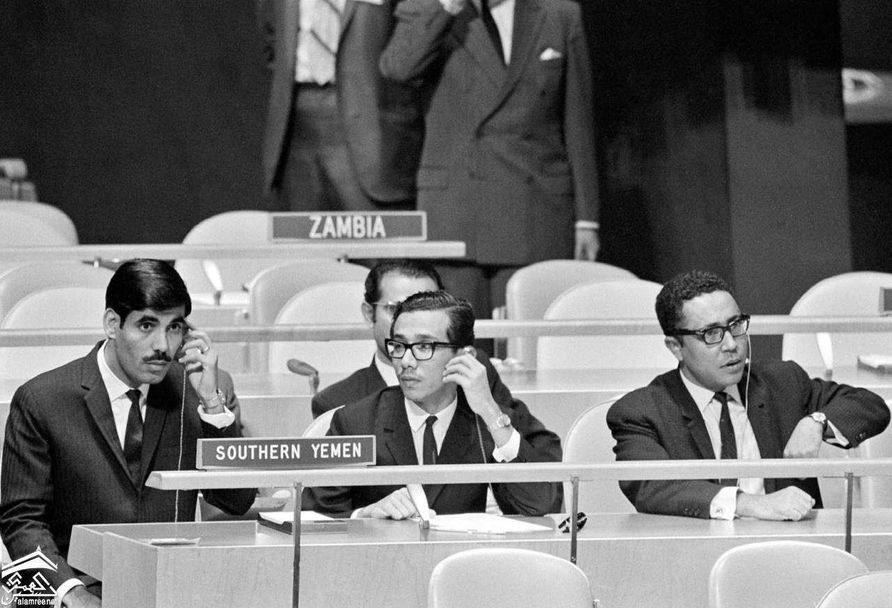 Three men from Southern Yemen hold phones during a formal international meeting.